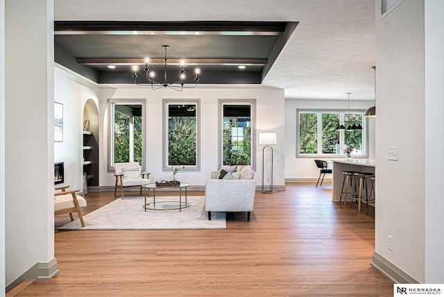 living room featuring a textured ceiling, light hardwood / wood-style floors, a chandelier, and a healthy amount of sunlight