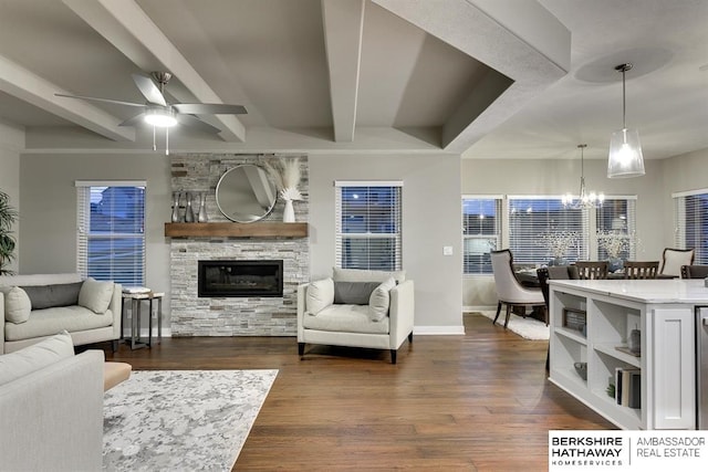 living room with beam ceiling, a stone fireplace, dark hardwood / wood-style flooring, and ceiling fan with notable chandelier