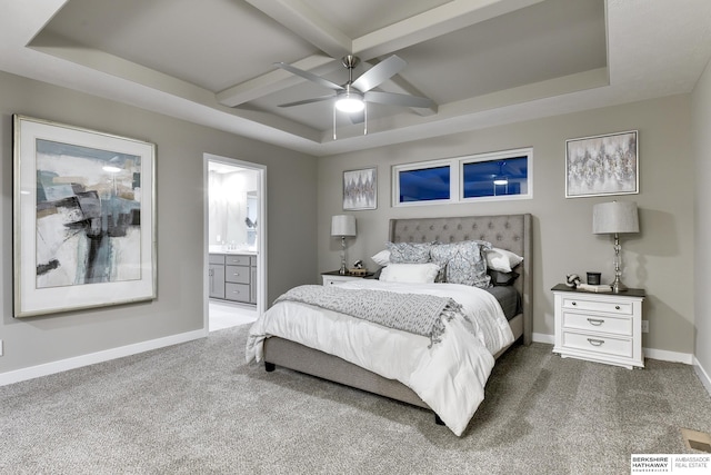 bedroom with connected bathroom, dark colored carpet, beam ceiling, ceiling fan, and a raised ceiling