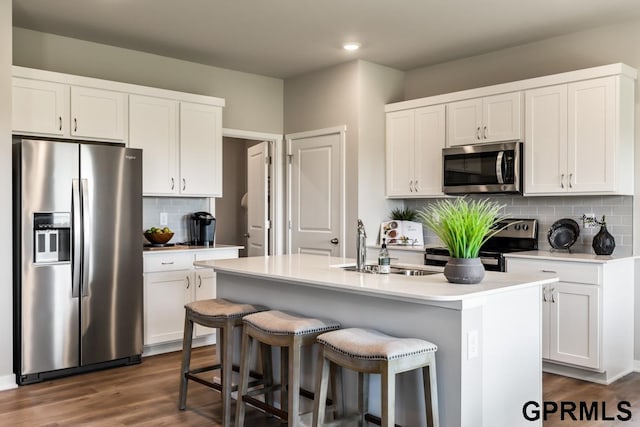 kitchen with white cabinets, stainless steel appliances, dark hardwood / wood-style floors, and a kitchen island with sink