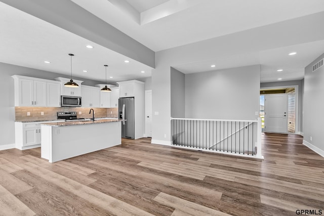 kitchen with white cabinetry, appliances with stainless steel finishes, light wood-type flooring, and a center island with sink