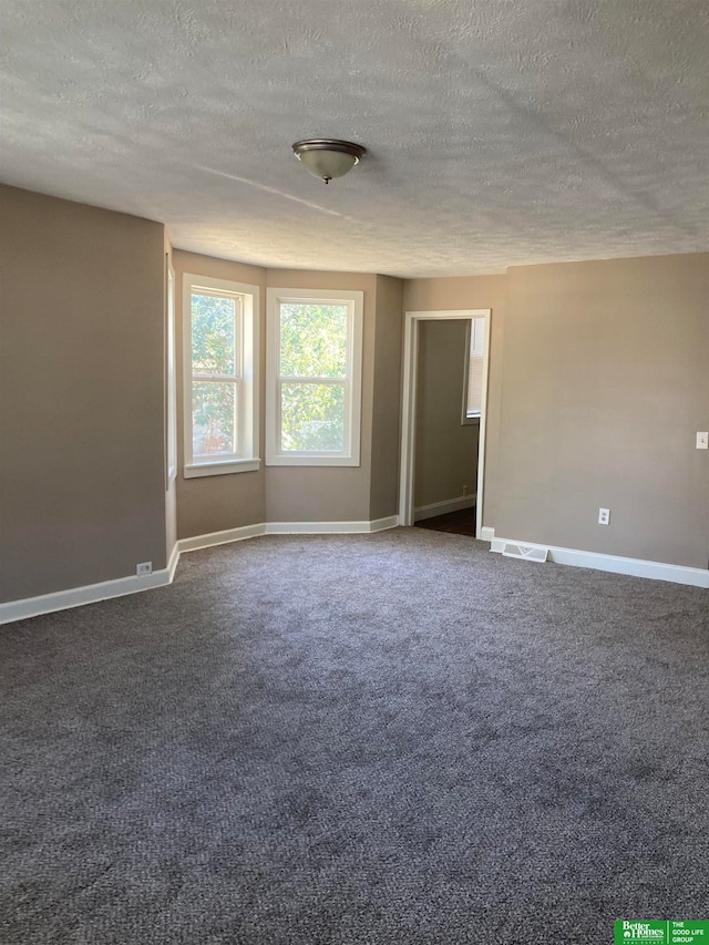 spare room with dark colored carpet and a textured ceiling