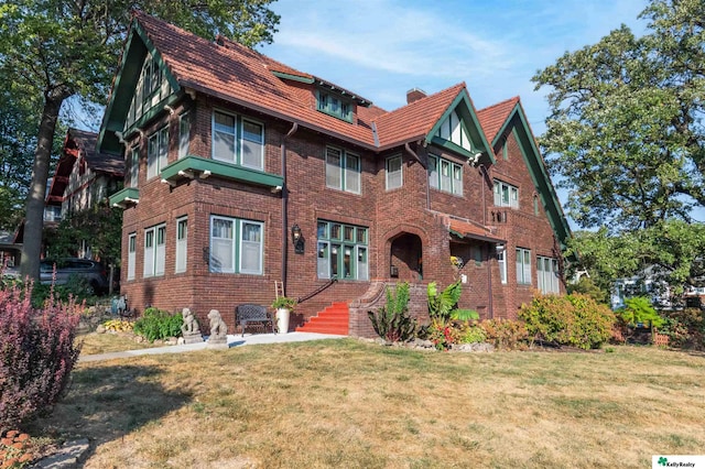 view of front of house with brick siding, a chimney, and a front lawn