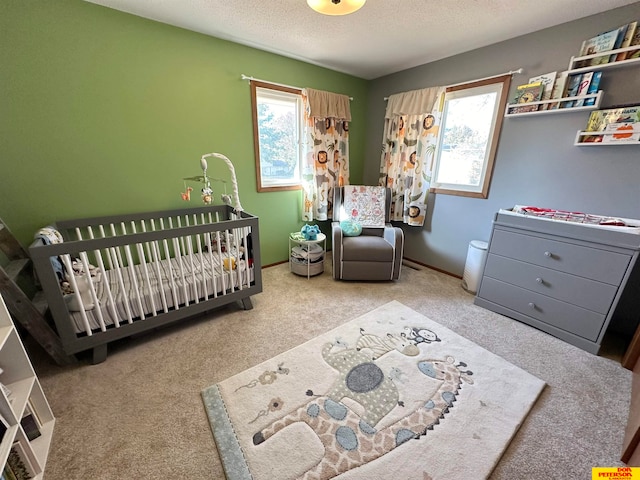 carpeted bedroom featuring a textured ceiling and a crib