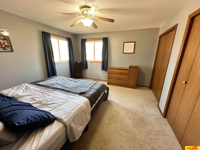 carpeted bedroom with ceiling fan and a textured ceiling