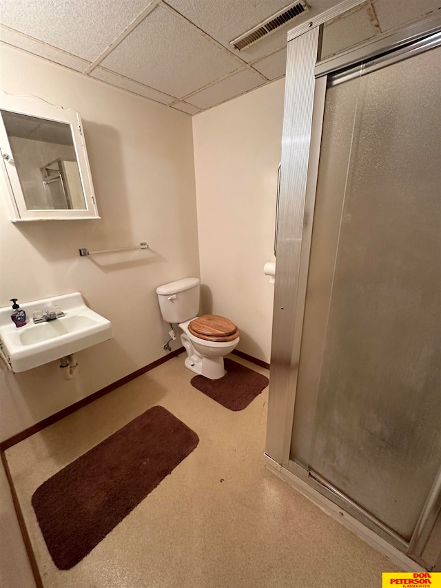 bathroom with toilet, sink, a paneled ceiling, and an enclosed shower