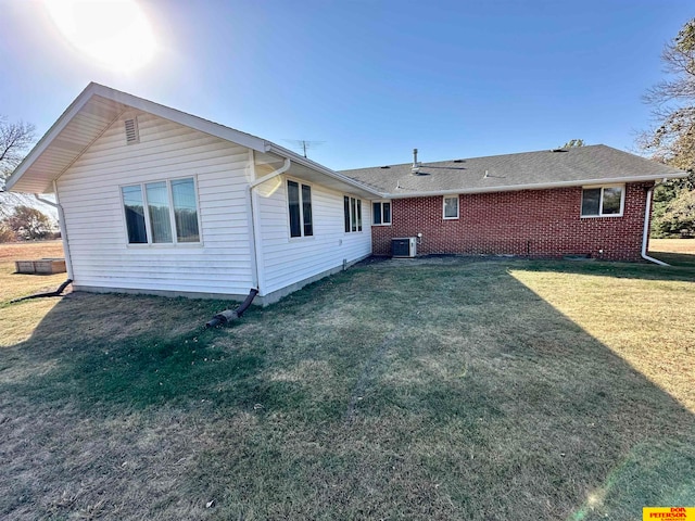 rear view of house featuring central AC and a yard