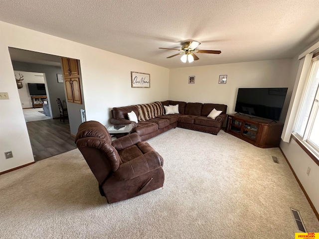 living room with carpet flooring, a textured ceiling, and ceiling fan