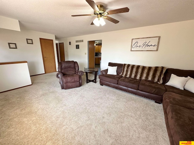 living room with a textured ceiling, light colored carpet, and ceiling fan