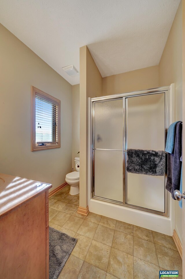 bathroom with toilet, walk in shower, and a textured ceiling