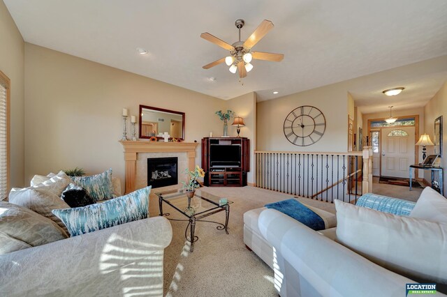 carpeted living room with a tile fireplace and ceiling fan