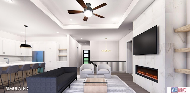 living room with a tray ceiling, wood-type flooring, ceiling fan with notable chandelier, a fireplace, and sink