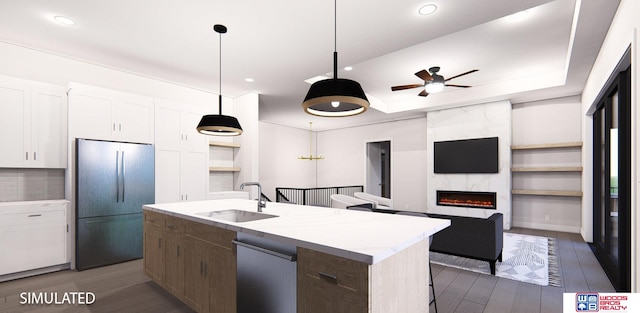 kitchen with fridge, a high end fireplace, stainless steel dishwasher, white cabinets, and a kitchen island with sink