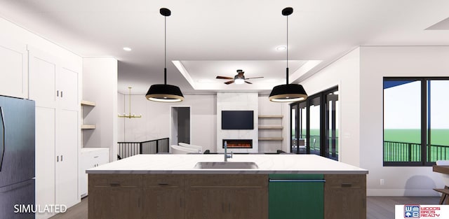 kitchen with white cabinets, black fridge, sink, and an island with sink