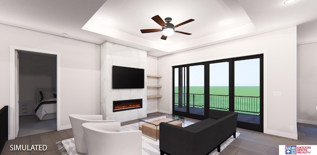 living room with ceiling fan, hardwood / wood-style flooring, a premium fireplace, and a raised ceiling