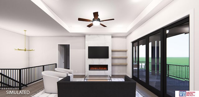 living room with a high end fireplace, ceiling fan with notable chandelier, hardwood / wood-style flooring, and a tray ceiling