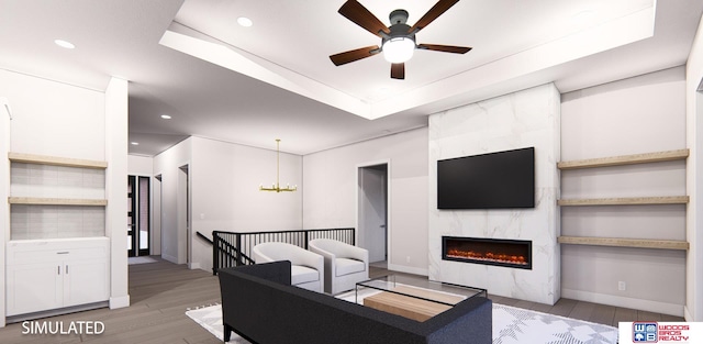 living room featuring a premium fireplace, ceiling fan with notable chandelier, and light wood-type flooring