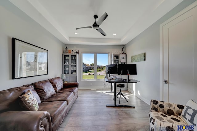 office space featuring a tray ceiling, wood-type flooring, and ceiling fan