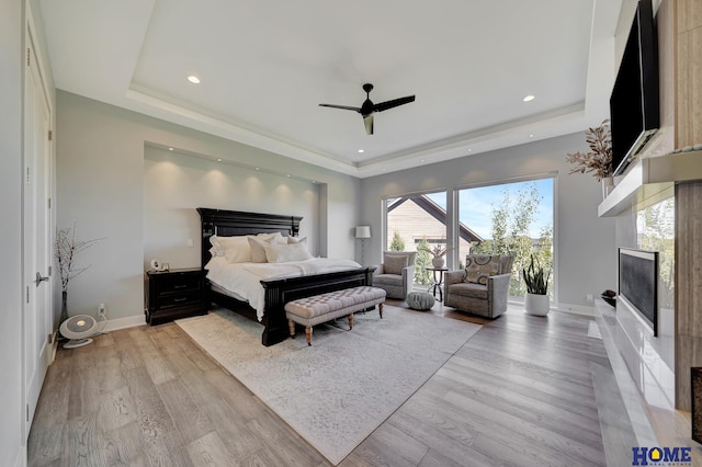 bedroom featuring a tray ceiling, light hardwood / wood-style floors, and ceiling fan