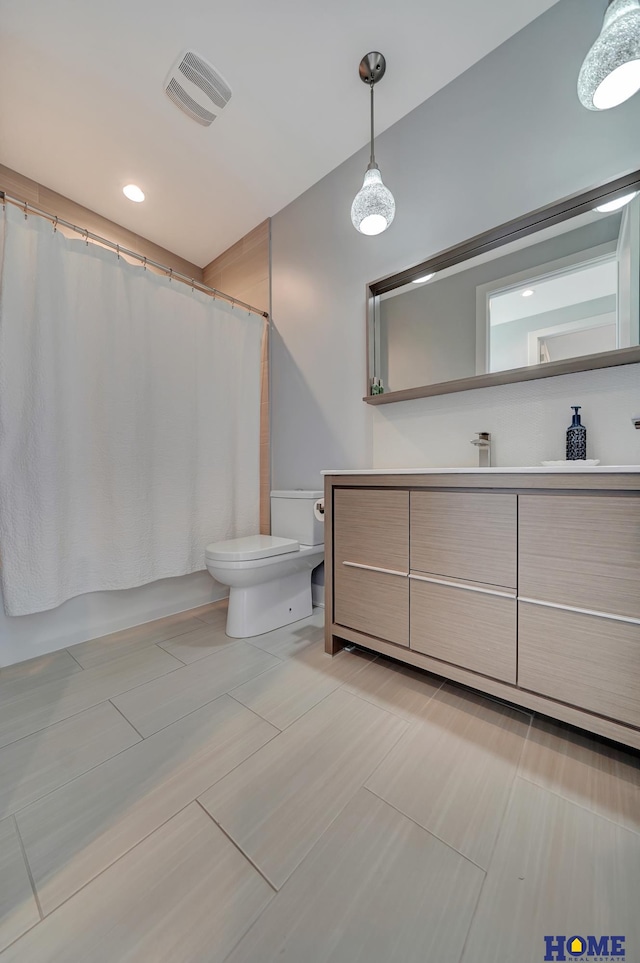 bathroom featuring vanity, walk in shower, and toilet