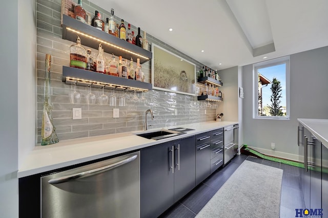 bar featuring dark tile patterned flooring, decorative backsplash, sink, and stainless steel dishwasher