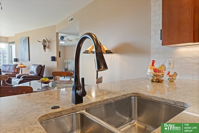 details with light stone countertops, sink, backsplash, and ceiling fan