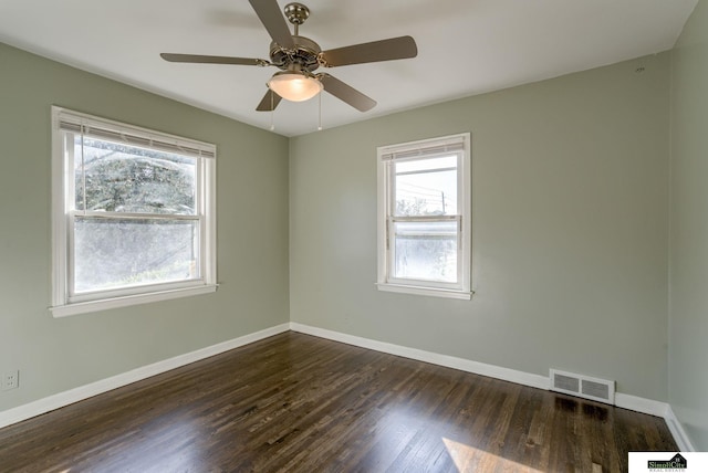 empty room featuring ceiling fan, dark wood-type flooring, and a wealth of natural light