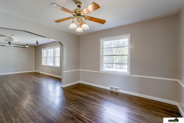 unfurnished room featuring ceiling fan, a healthy amount of sunlight, and dark hardwood / wood-style flooring