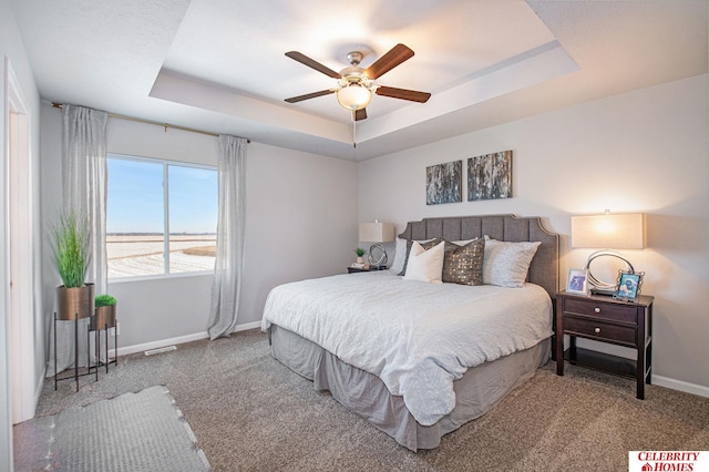 carpeted bedroom featuring ceiling fan and a raised ceiling