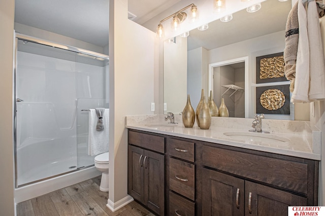 bathroom with toilet, hardwood / wood-style flooring, vanity, and a shower with door