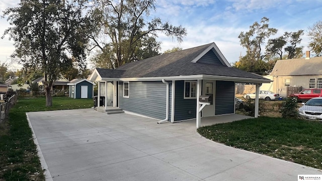 view of front of home featuring a shed, a front yard, a porch, and a carport