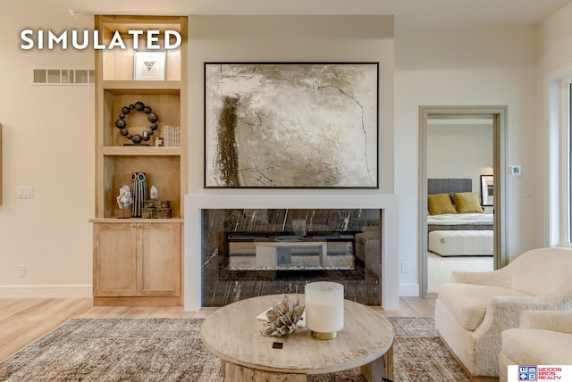 living room with a premium fireplace, built in shelves, and hardwood / wood-style flooring