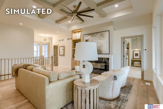 living room featuring beam ceiling, coffered ceiling, light wood-type flooring, and ceiling fan with notable chandelier