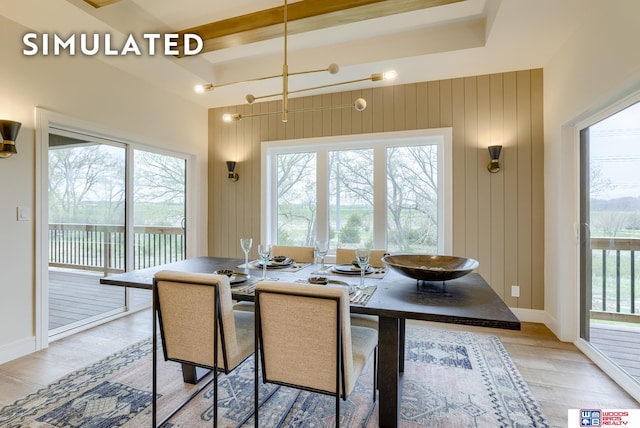 dining room with an inviting chandelier, light hardwood / wood-style flooring, wood walls, and plenty of natural light