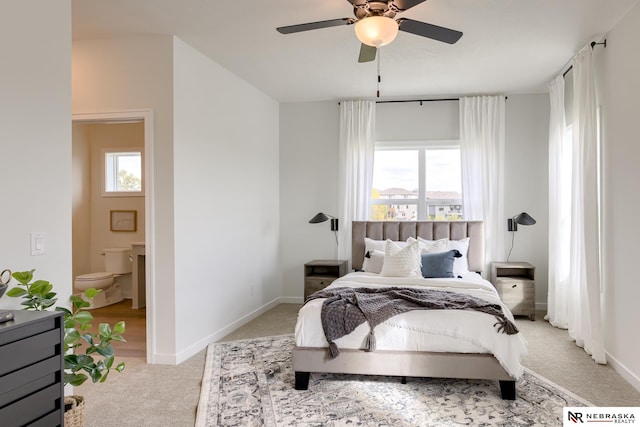 bedroom with ensuite bathroom, light carpet, and ceiling fan