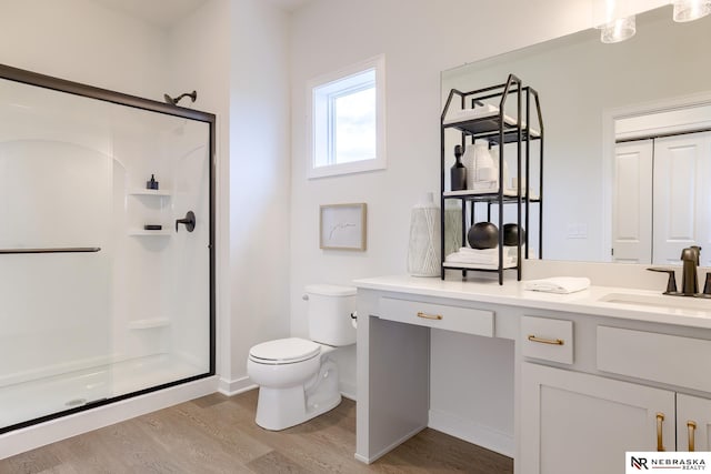 bathroom featuring vanity, toilet, a shower with shower door, and wood-type flooring