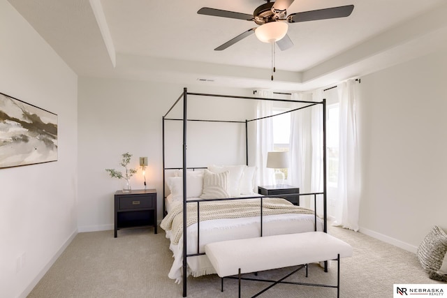 carpeted bedroom featuring a tray ceiling and ceiling fan