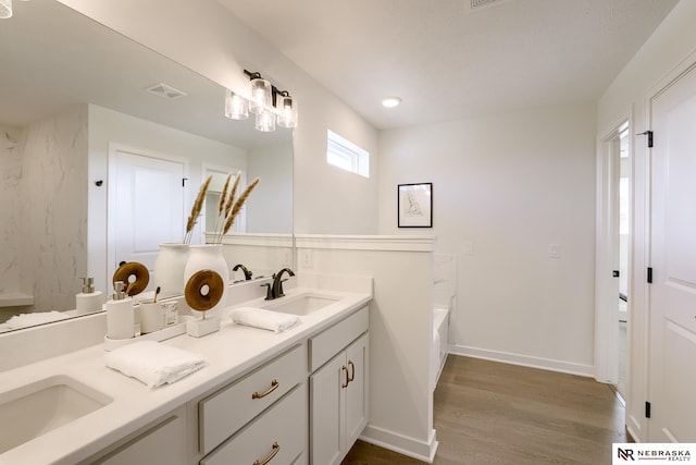 bathroom with vanity, hardwood / wood-style floors, and a bath