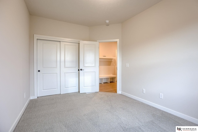 unfurnished bedroom featuring light colored carpet and a closet