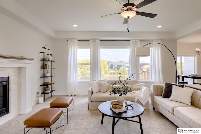 living room featuring ceiling fan, light colored carpet, and a fireplace