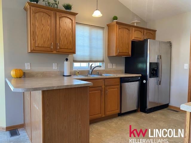 kitchen with lofted ceiling, light tile patterned floors, stainless steel appliances, sink, and decorative light fixtures