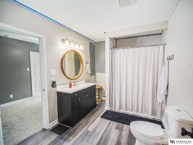 bathroom with vanity, hardwood / wood-style floors, a textured ceiling, and toilet