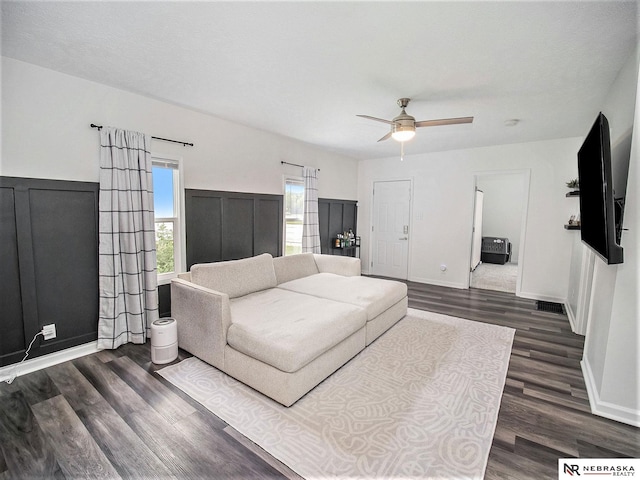 living room with dark wood-type flooring, a textured ceiling, and ceiling fan