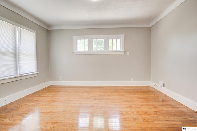 spare room with ornamental molding and light wood-type flooring