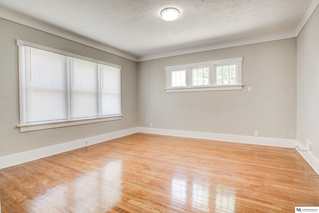 spare room featuring crown molding, a textured ceiling, and light hardwood / wood-style flooring