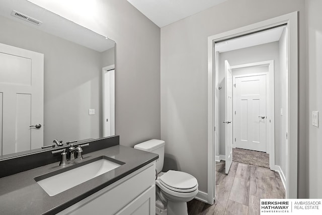 bathroom with vanity, toilet, and wood-type flooring