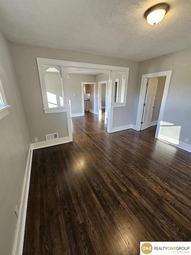 unfurnished room featuring a textured ceiling and dark hardwood / wood-style flooring