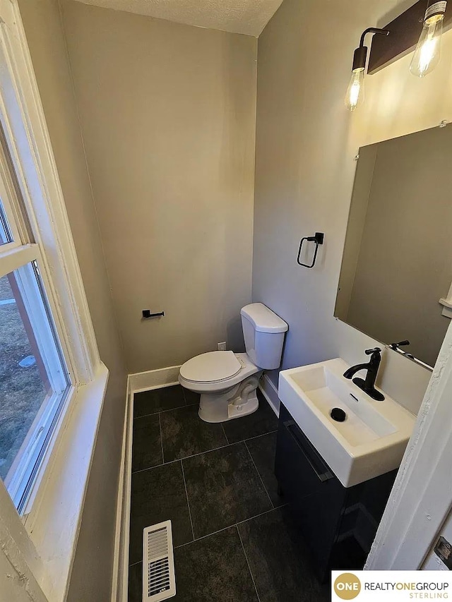 bathroom featuring vanity, a textured ceiling, toilet, and tile patterned flooring