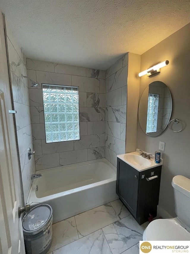 full bathroom featuring tiled shower / bath, vanity, a textured ceiling, and toilet