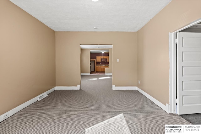 empty room with carpet and a textured ceiling